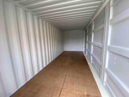 Binnenkant Een hoogwaardige 20FT open side zeecontainer, eerste reis, slechts één keer gebruikt voor verscheping. Uitgevoerd in wit (RAL 9010), met Cor-Ten-stalen wanden (1,50 mm dik), een geprofileerd dak (2,00 mm dik) en een houten vloer. Wind- en waterdicht en voorzien van gegalvaniseerde deursluitingen. Dankzij de dubbele toegang via de korte én lange zijde is deze container ideaal voor efficiënte opslag en transport.
